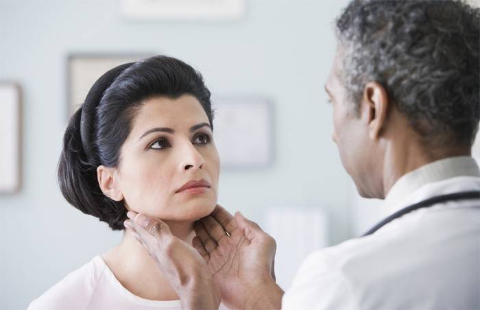 El médico siente la glándula tiroides de una mujer.