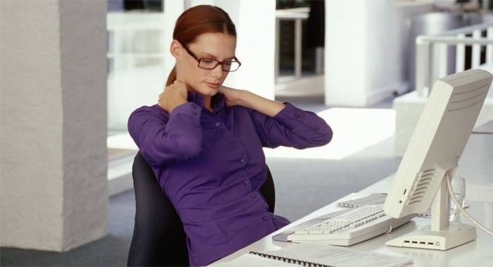 Niña amasa su espalda, sentada en el trabajo