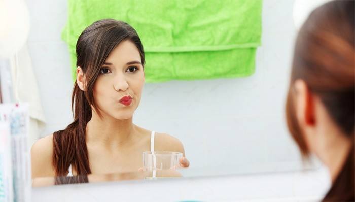 Niña se enjuaga la boca después de la extracción del diente