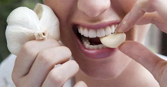 Menina morde um dente de alho