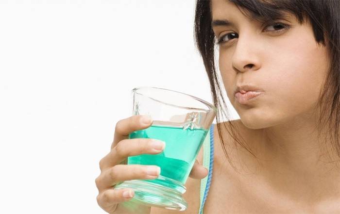 La mujer se enjuaga la boca después de la extracción del diente