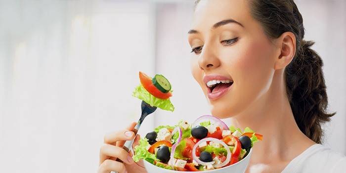 Dziewczyna je sałatki warzywne zgodnie z dietą, aby wyszczuplić nogi i biodra