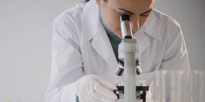 Laboratórny technik pri pohľade cez mikroskop