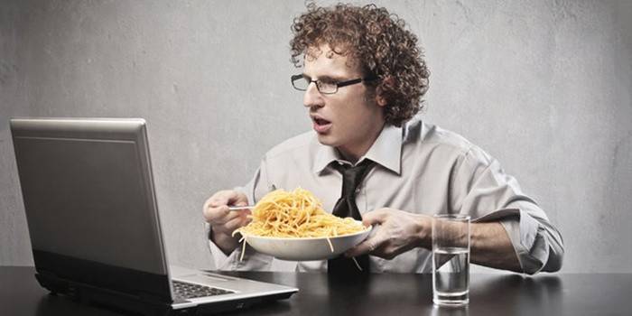 El chico está comiendo en la computadora