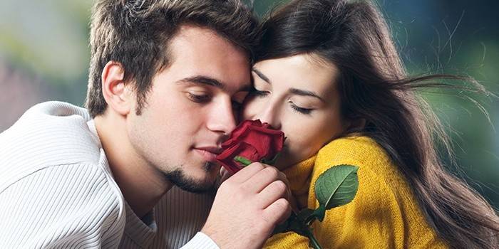 Garoto e garota cheirando uma rosa