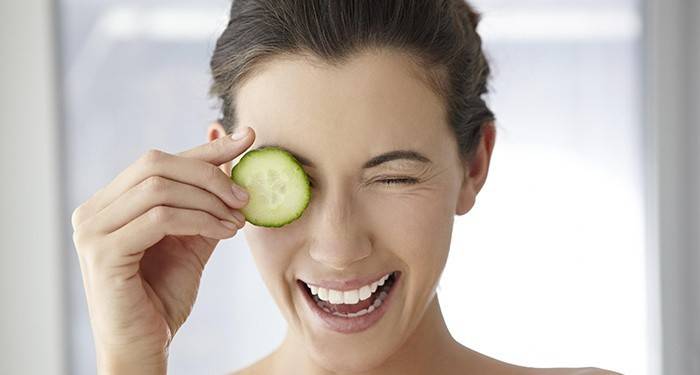 Garota faz uma máscara de pepino de círculos sob os olhos