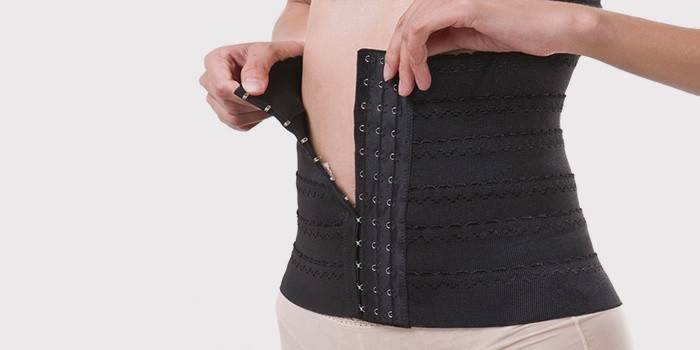 A menina prende o espartilho do emagrecimento da barriga
