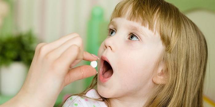 Mamãe dá ao bebê uma pílula para amigdalite