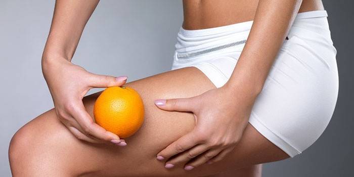 Chica sosteniendo una naranja en sus manos