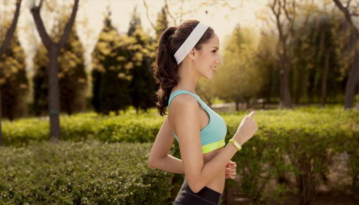 Dziewczyna biegnie z inteligentną bransoletką fitness