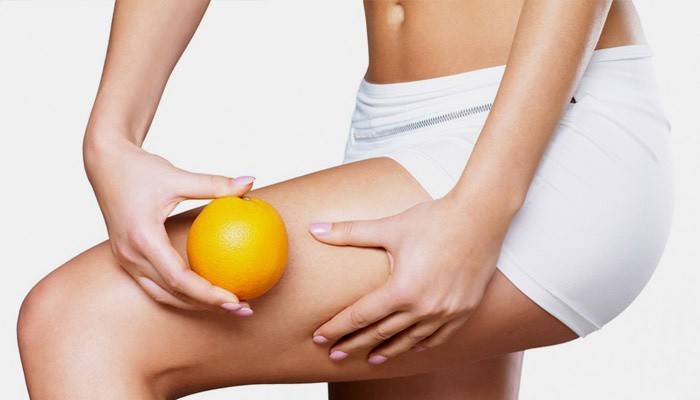 Dievča s oranžovou ukazuje stehná bez celulitídy