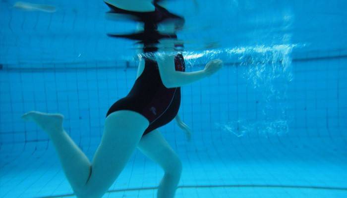 Niña embarazada nada en la piscina