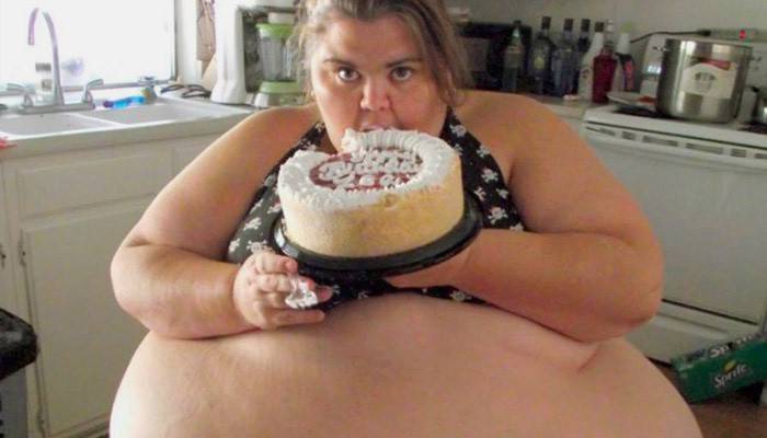 Mujer obesa comiendo un pastel