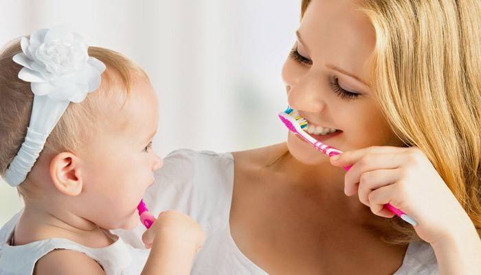 Mãe e filha escovam os dentes