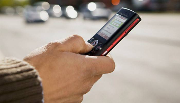 Mężczyzna wybiera numer SMS na telefonie komórkowym