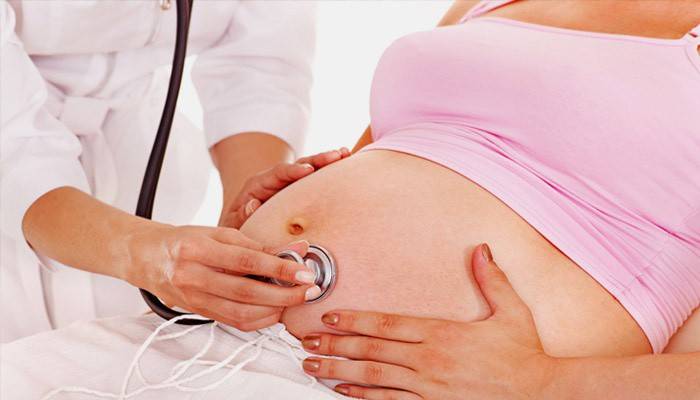 Médico examina a una mujer embarazada