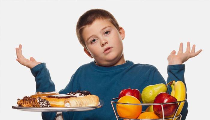 El niño elige entre frutas y dulces.