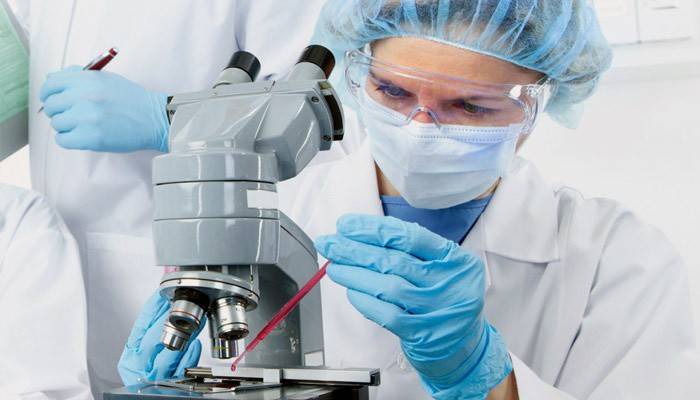 Asistente de laboratorio examina un análisis de sangre