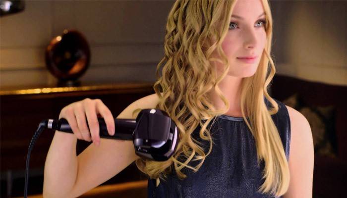 Chica alisa el cabello con styler