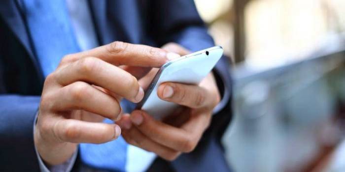 Mężczyzna trzyma smartphone w ręce.