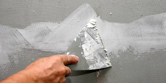 Massa de vidraceiro com uma espátula sob papel de parede