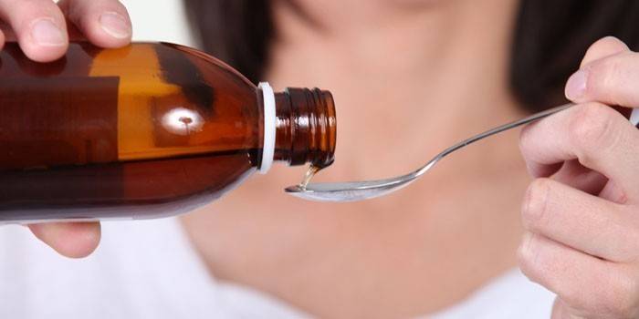 Žena naleje sirup do lyžice