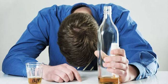 Muž s fľašou a pohárom alkoholu