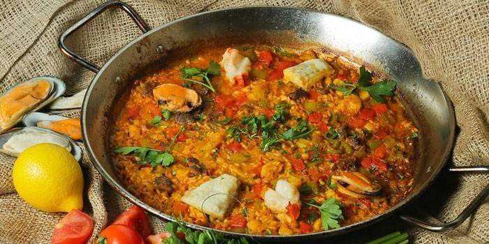Paella com peixe e cogumelos em uma panela