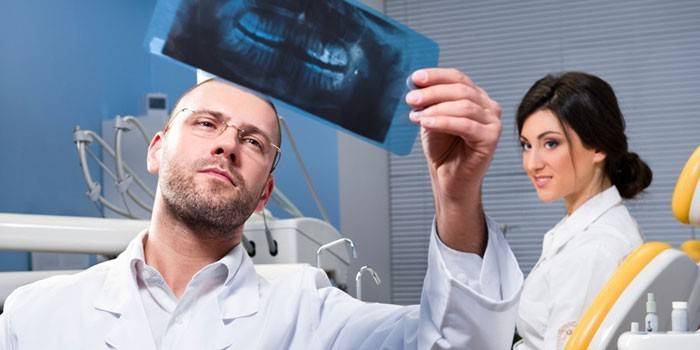 El médico mira los dientes del paciente.