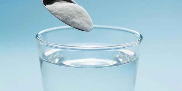 Alkobarrier em pó em uma colher e um copo de água