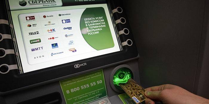Muž vloží kartu do bankomatu