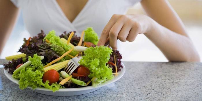 Menina come salada de legumes