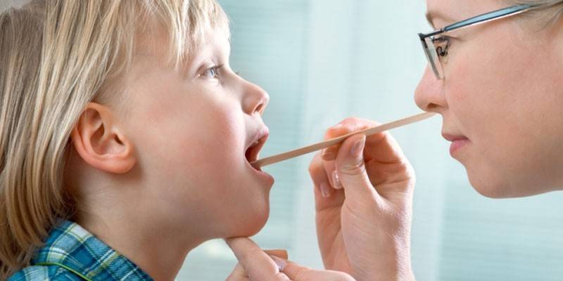El médico examina la garganta de un niño.