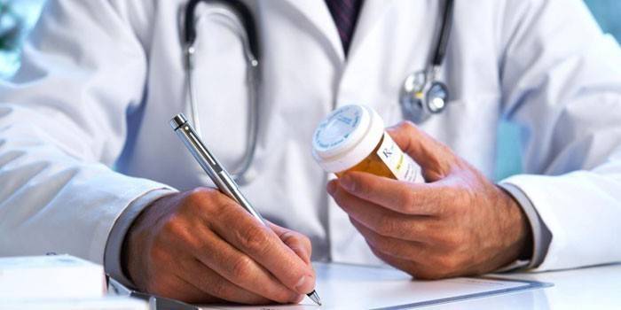 Doktor píše predpis a má v ruke balenie tabliet