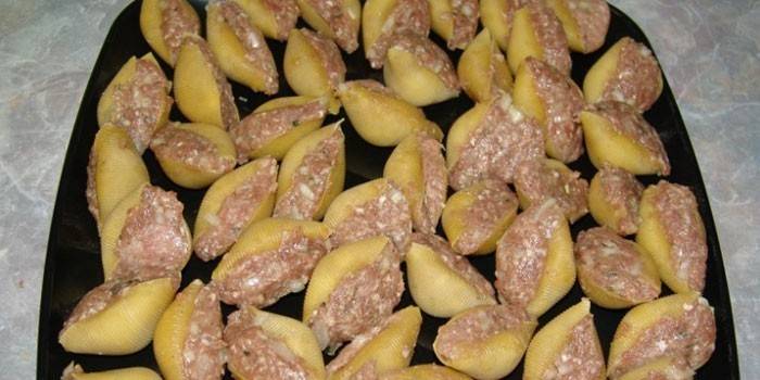 Conchas rellenas de carne en una bandeja para hornear antes de hornear