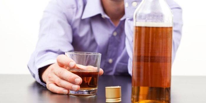 Muž a whisky v pohári a fľaši