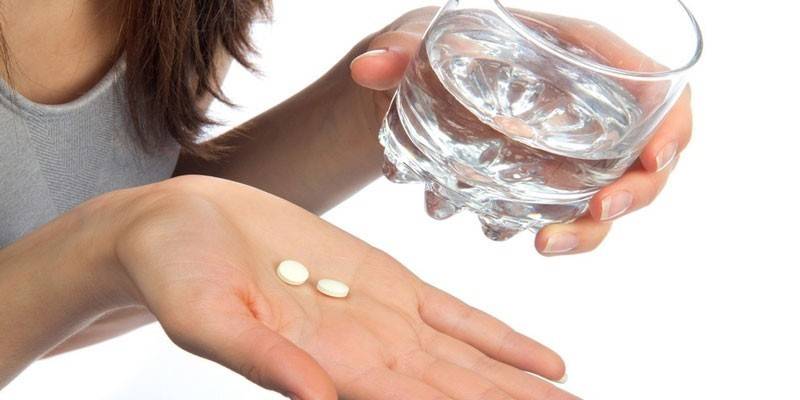 Um copo de água e remédio na palma da sua mão