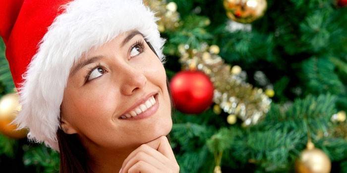 Dievča v klobúku Santa Clausa na pozadí vianočného stromu