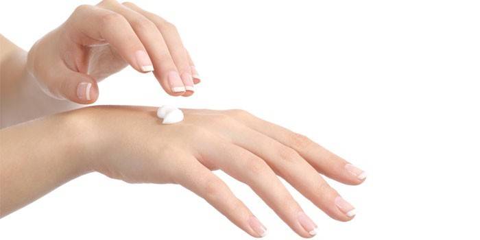 Mulher coloca creme nas mãos dela