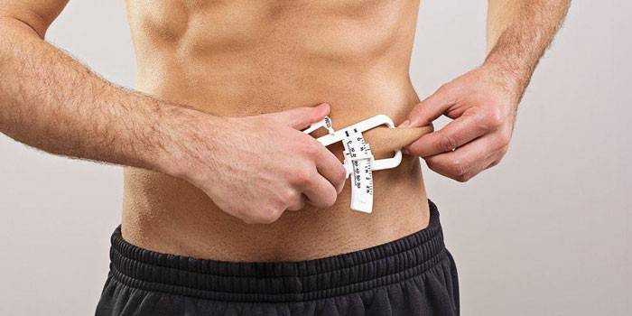 Um homem mede a porcentagem de gordura com um paquímetro