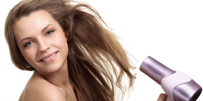 Menina seca o cabelo com secador de cabelo