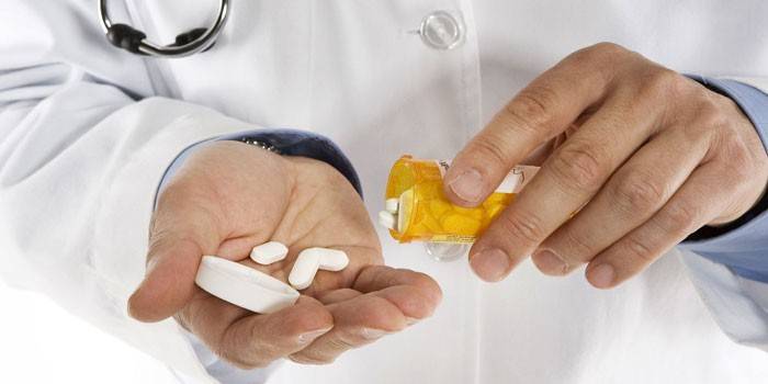 Medic vertiendo pastillas de un frasco en la palma de su mano
