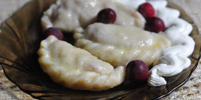Pierogi wiśniowe z kwaśną śmietaną na talerzu