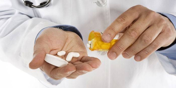 Comprimidos blancos en la palma de un médico.
