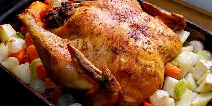 Pollo entero con verduras en una bandeja para hornear