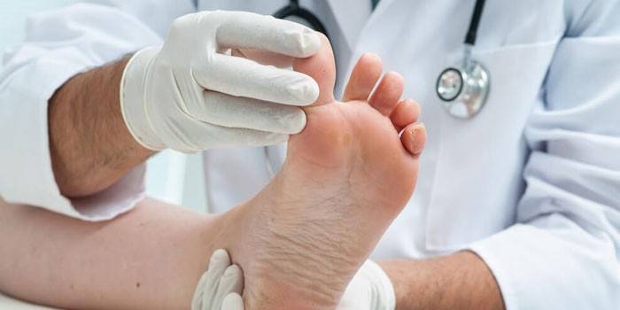 El médico examina la pierna del paciente.