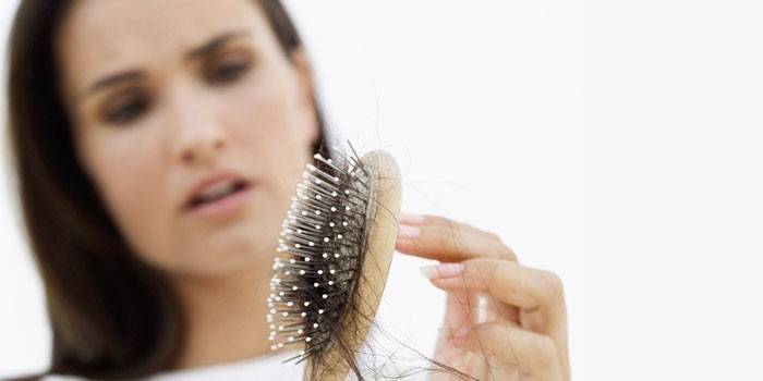 A menina olha para o pente com o cabelo dela