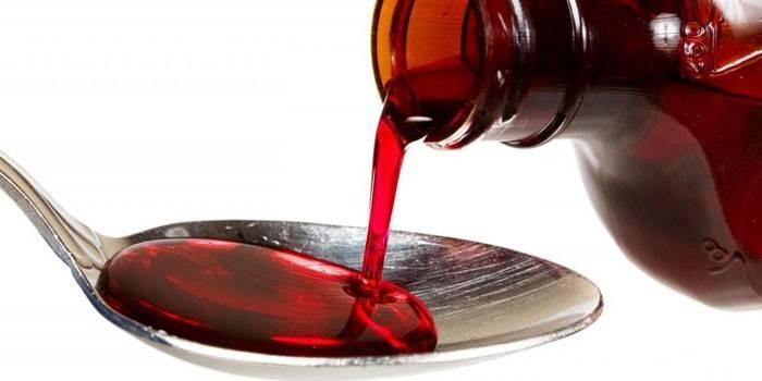Syrop wlewa się z butelki do łyżki