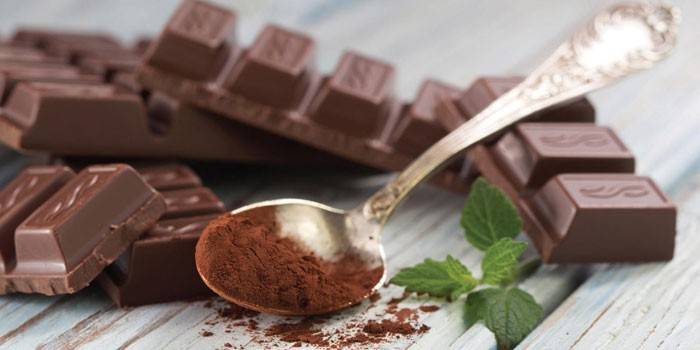 Barras de chocolate negro y cacao en una cuchara.