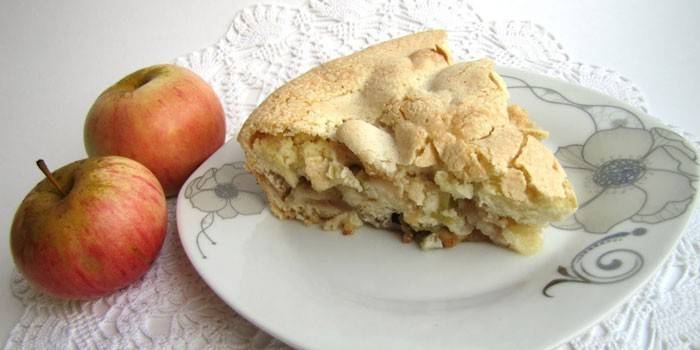 Uma fatia de torta de maçã em um prato e maçãs